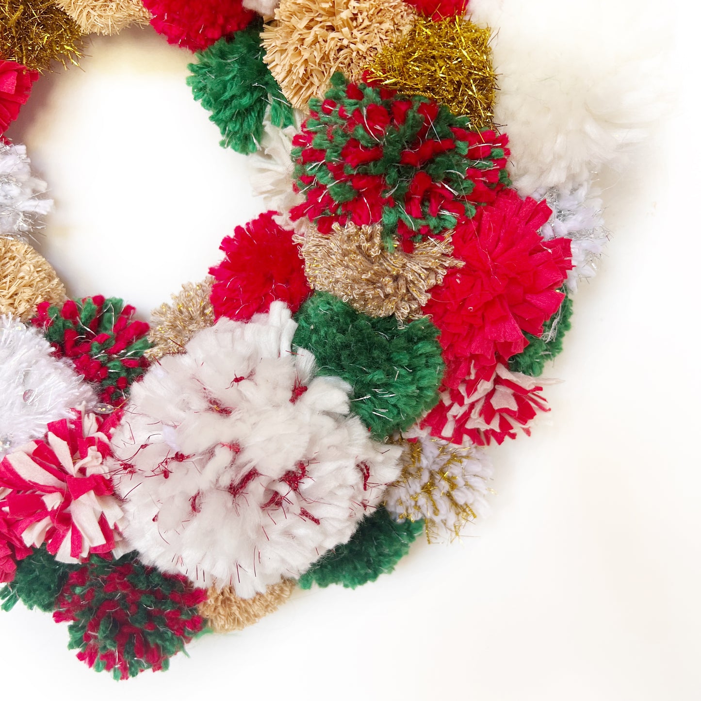 close up of Red, Green, White Pom Pom Christmas Wreath. Handmade using a variety of yarns.