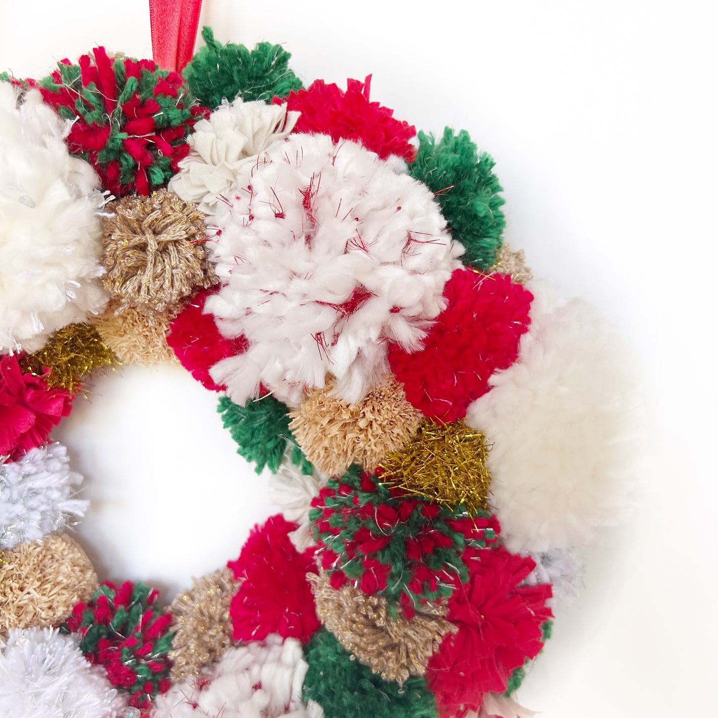 Close Up of Red, Green, White Pom Pom Christmas Wreath. Handmade using a variety of yarns.