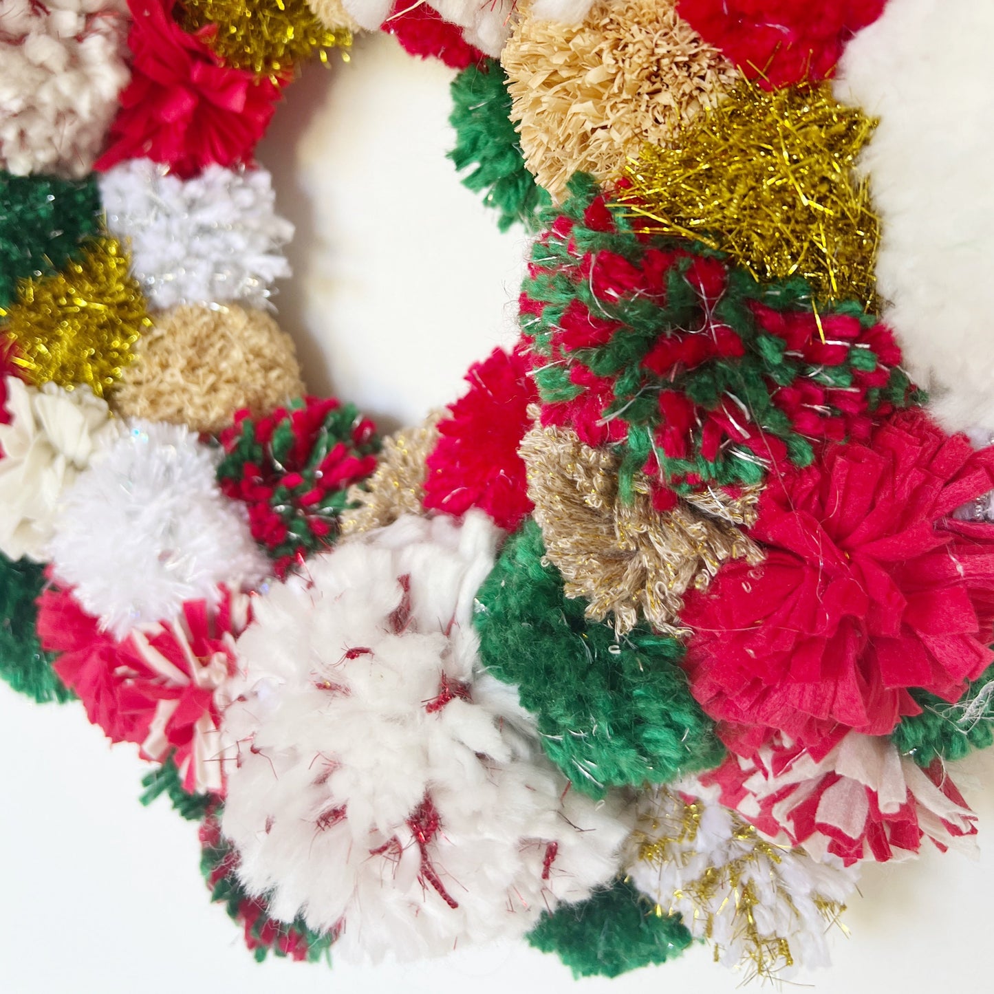 Up Close image of our Red, Green, White Pom Pom Christmas Wreath. Handmade using a variety of yarns.