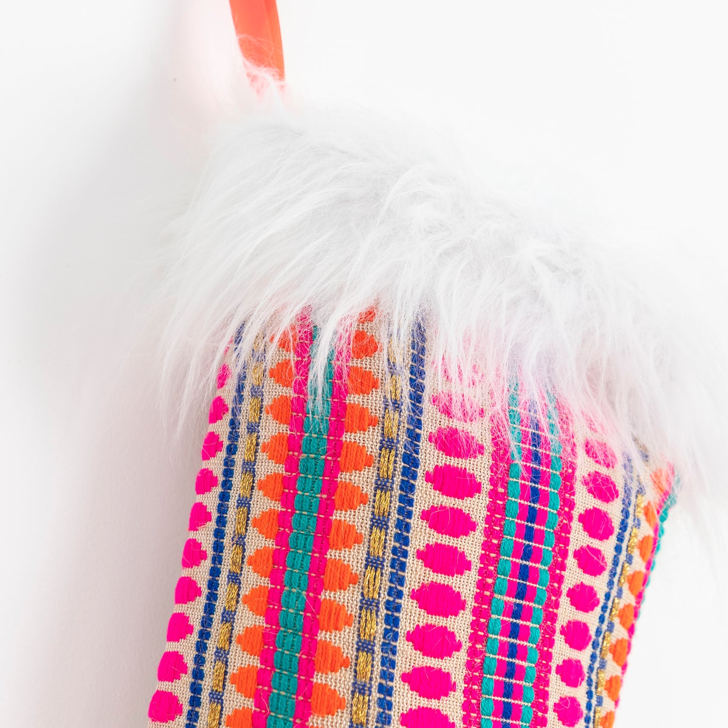 close up of: beautiful woven pink fabric stocking with faux fur trim hanging by a bright orange ribbon.