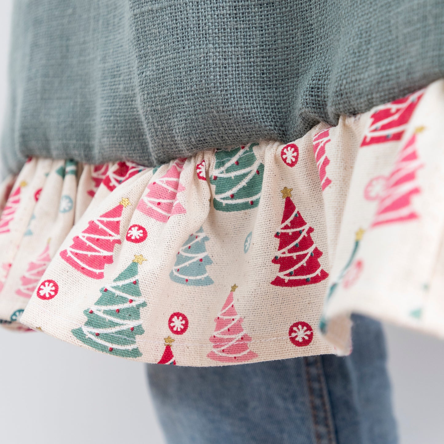 close up of frill on hem green linen apron with christmas fabric on pocket and frill