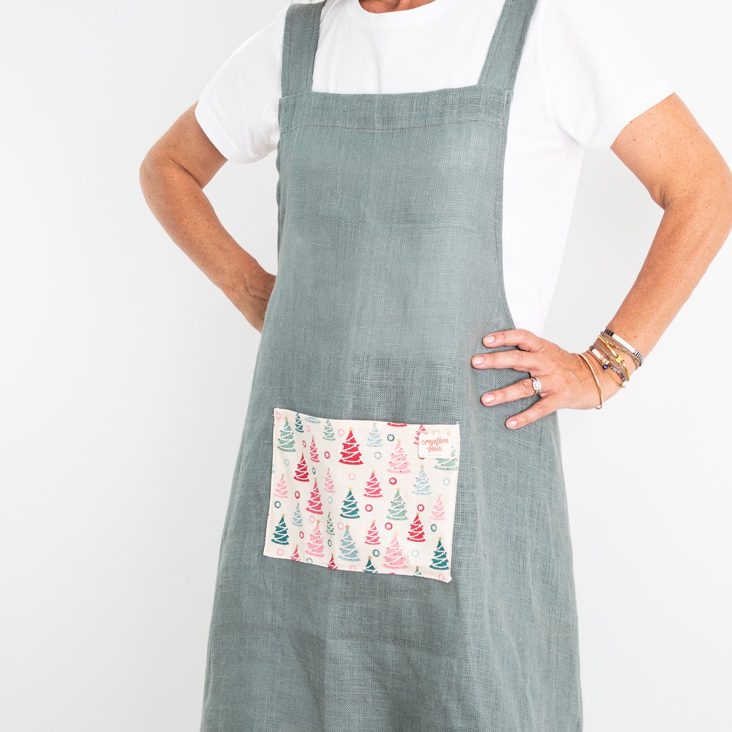front view of cross back apron - green linen with feature pocket and frill
