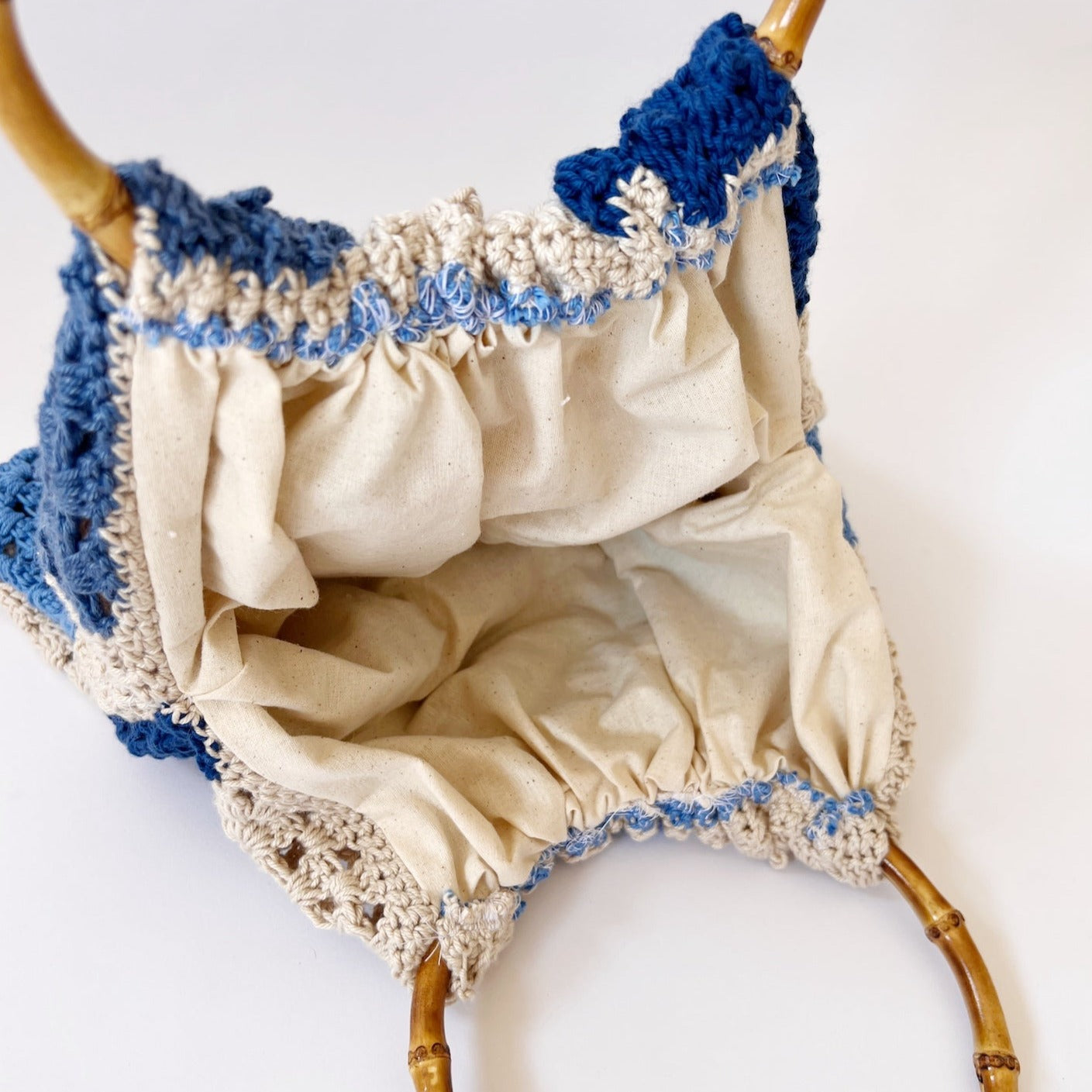 blue and cream crochet bag with bamboo handles.