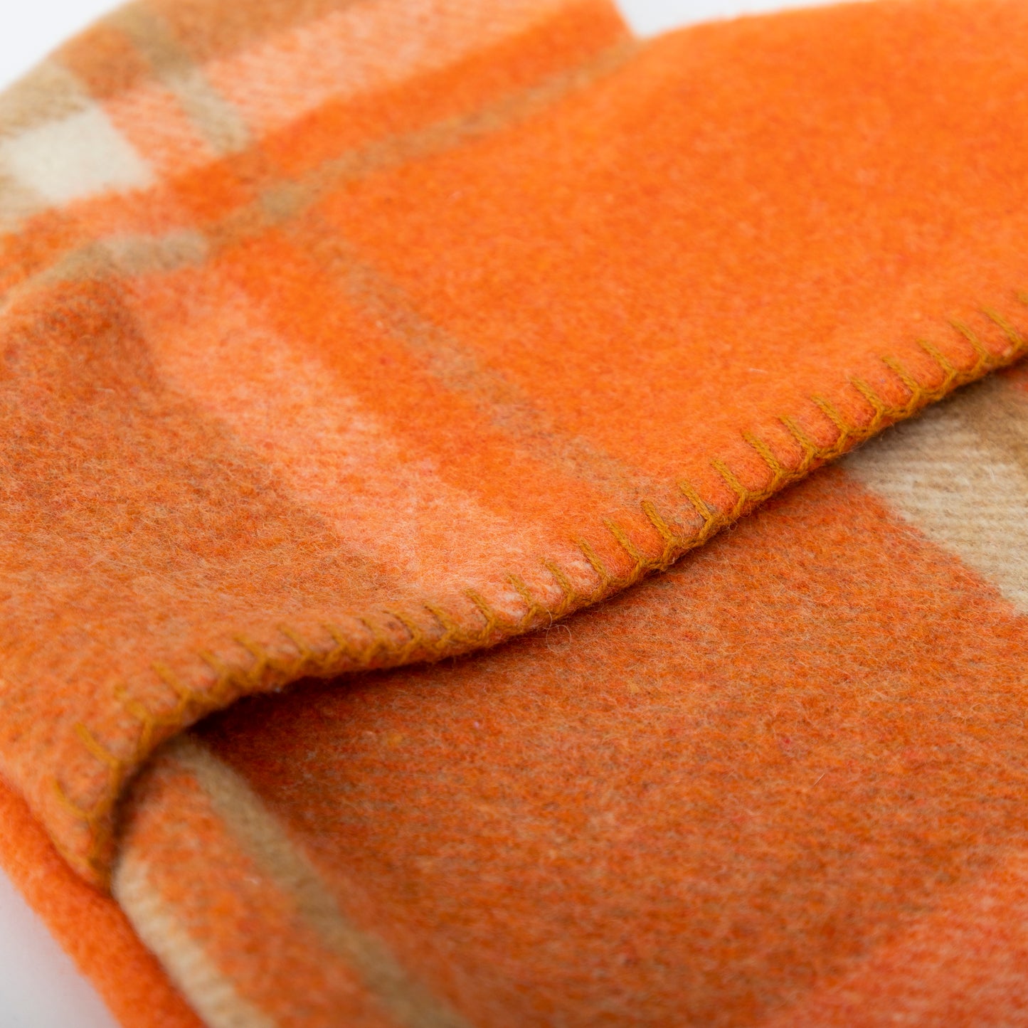 Up close image of the blanket stitching on the orange hot water bottle cover