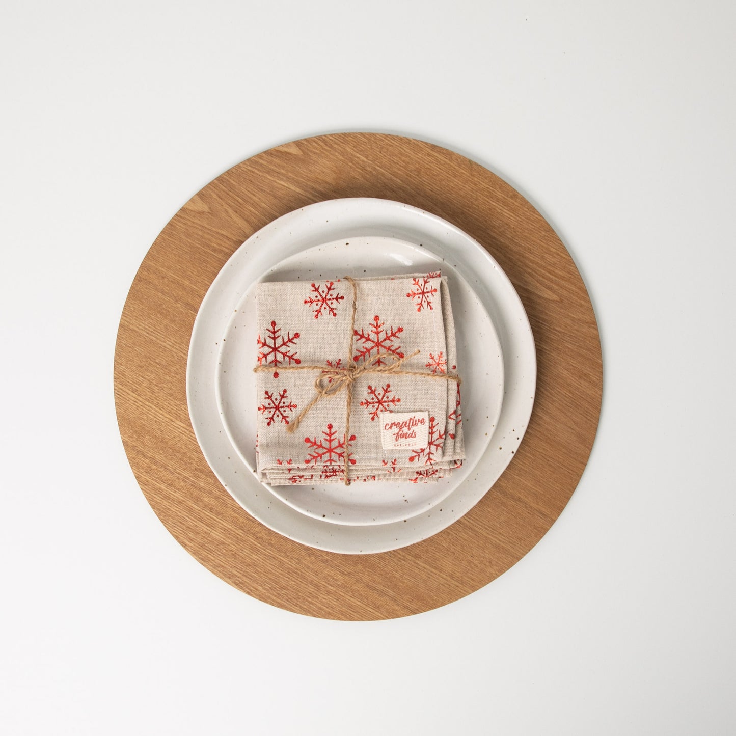 Set of four christmas snowflake napkins tied with string sitting on white plates