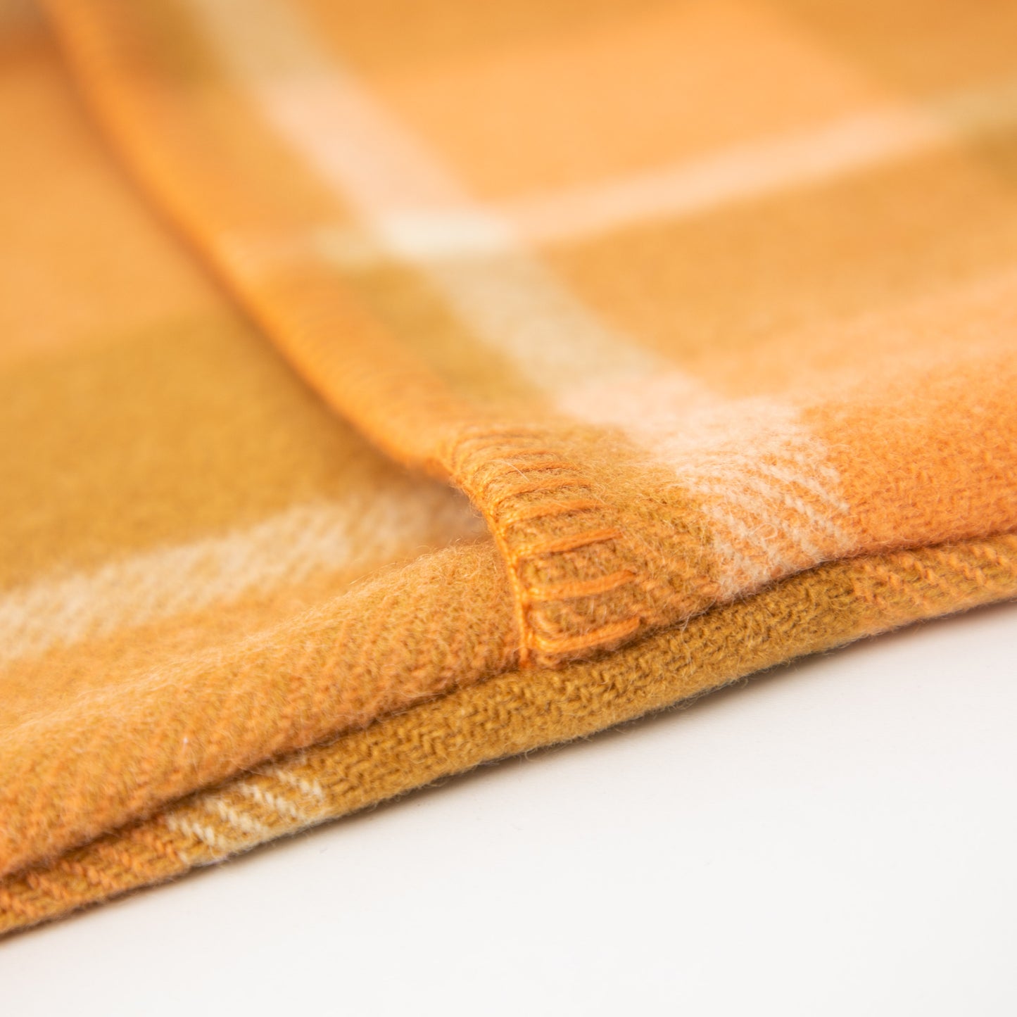 Up close image of the blanket stitching on the apricot hot water bottle cover
