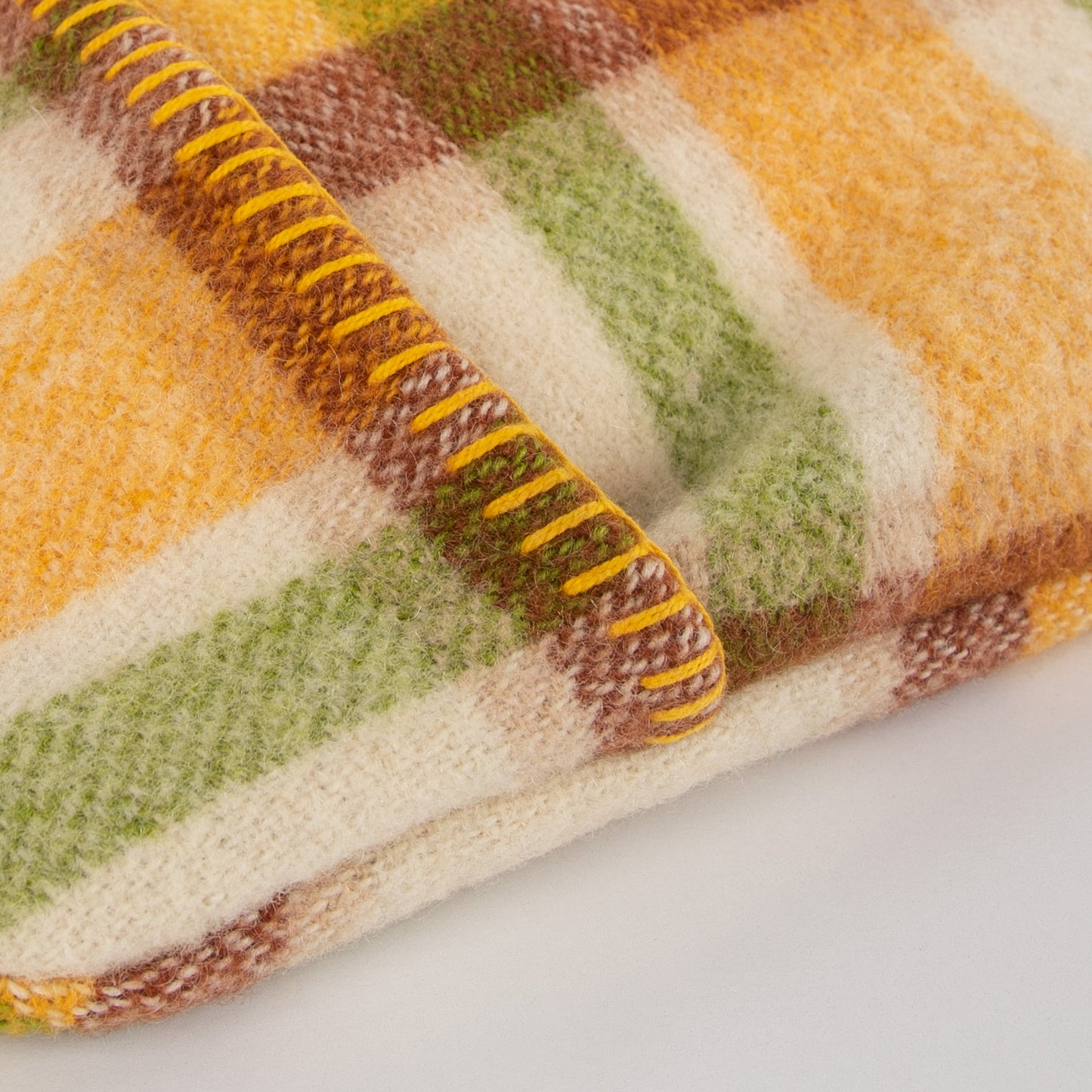 Up close image of the blanket stitching on the yellow, green & brown hot water bottle cover