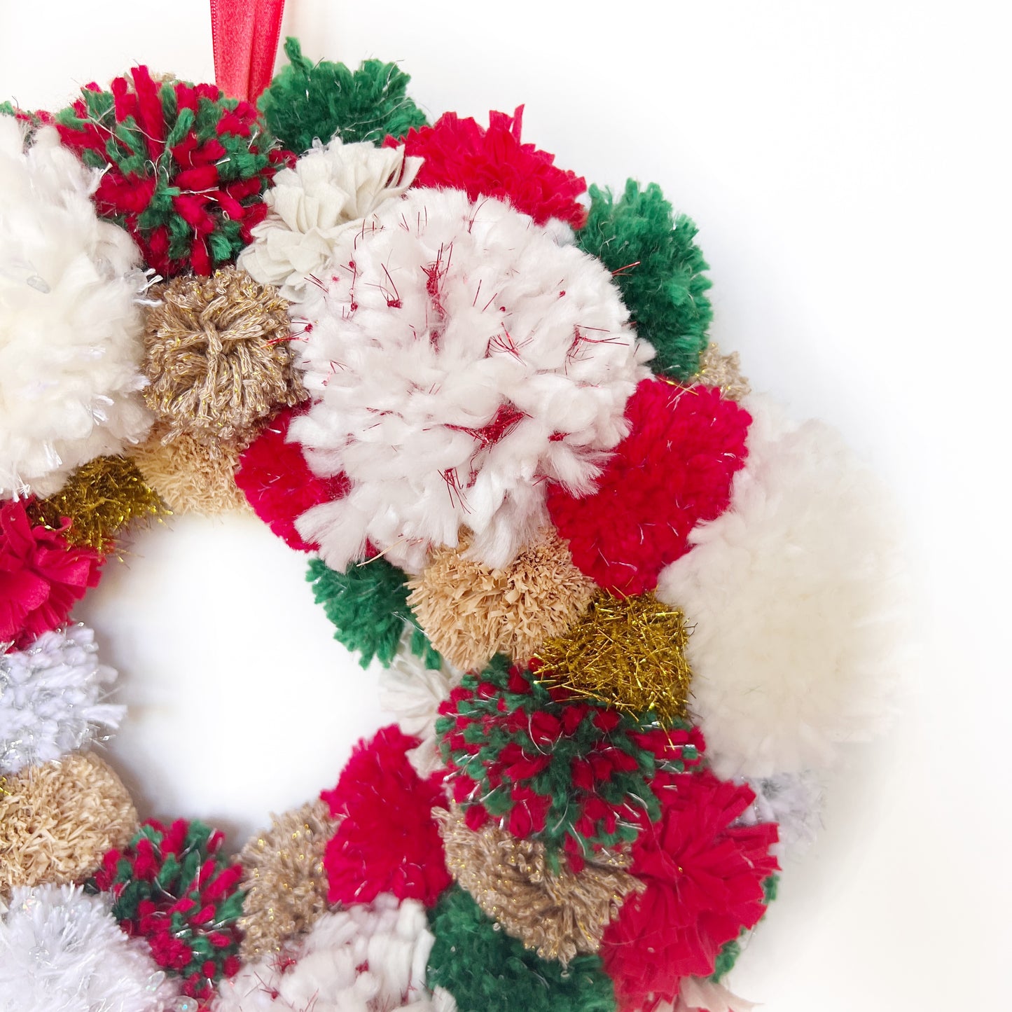 
                  
                    Close Up of Red, Green, White Pom Pom Christmas Wreath. Handmade using a variety of yarns.
                  
                