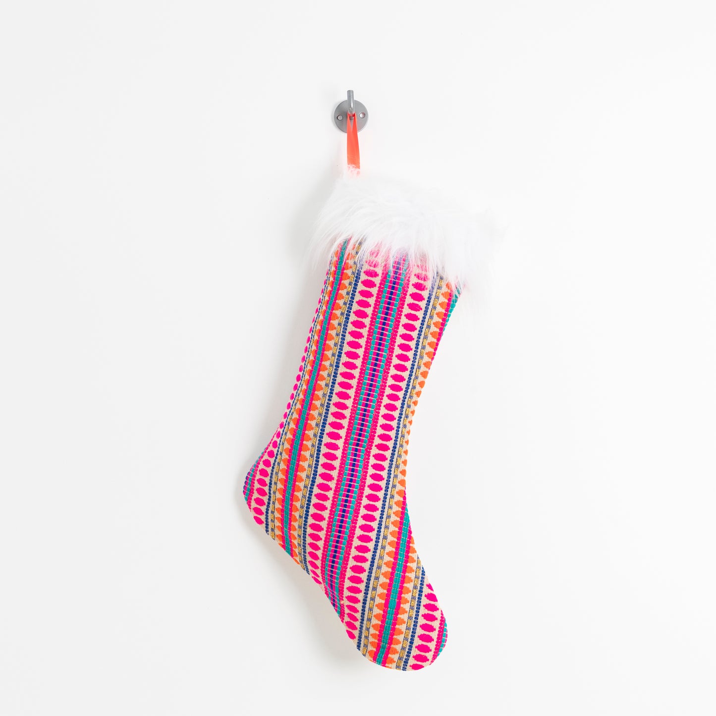 beautiful woven pink fabric stocking with faux fur trim hanging by a bright orange ribbon.