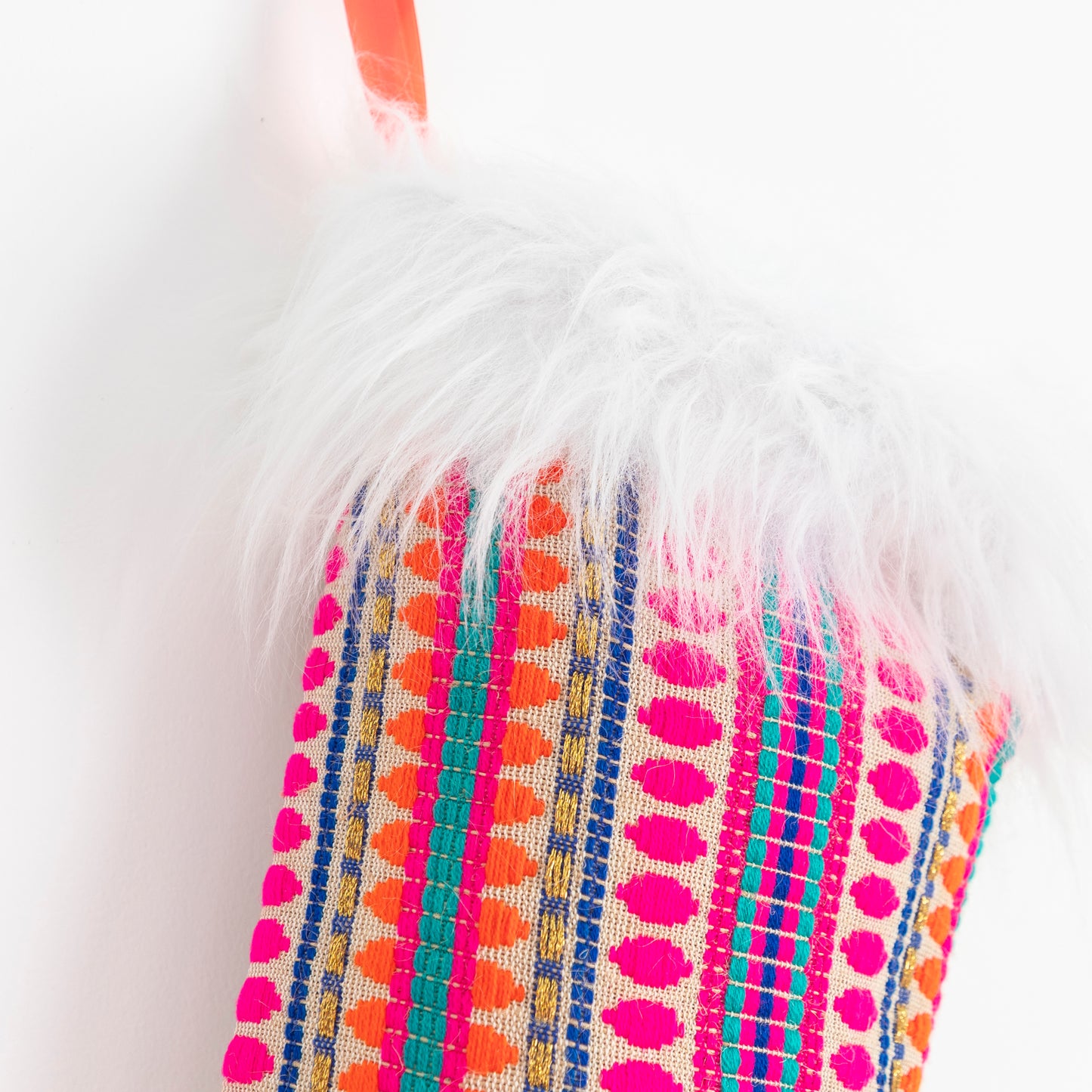 
                  
                    close up of: beautiful woven pink fabric stocking with faux fur trim hanging by a bright orange ribbon.
                  
                