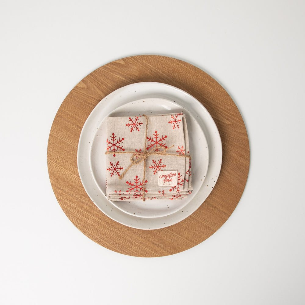 
                  
                    Set of four christmas snowflake napkins tied with string sitting on white plates
                  
                