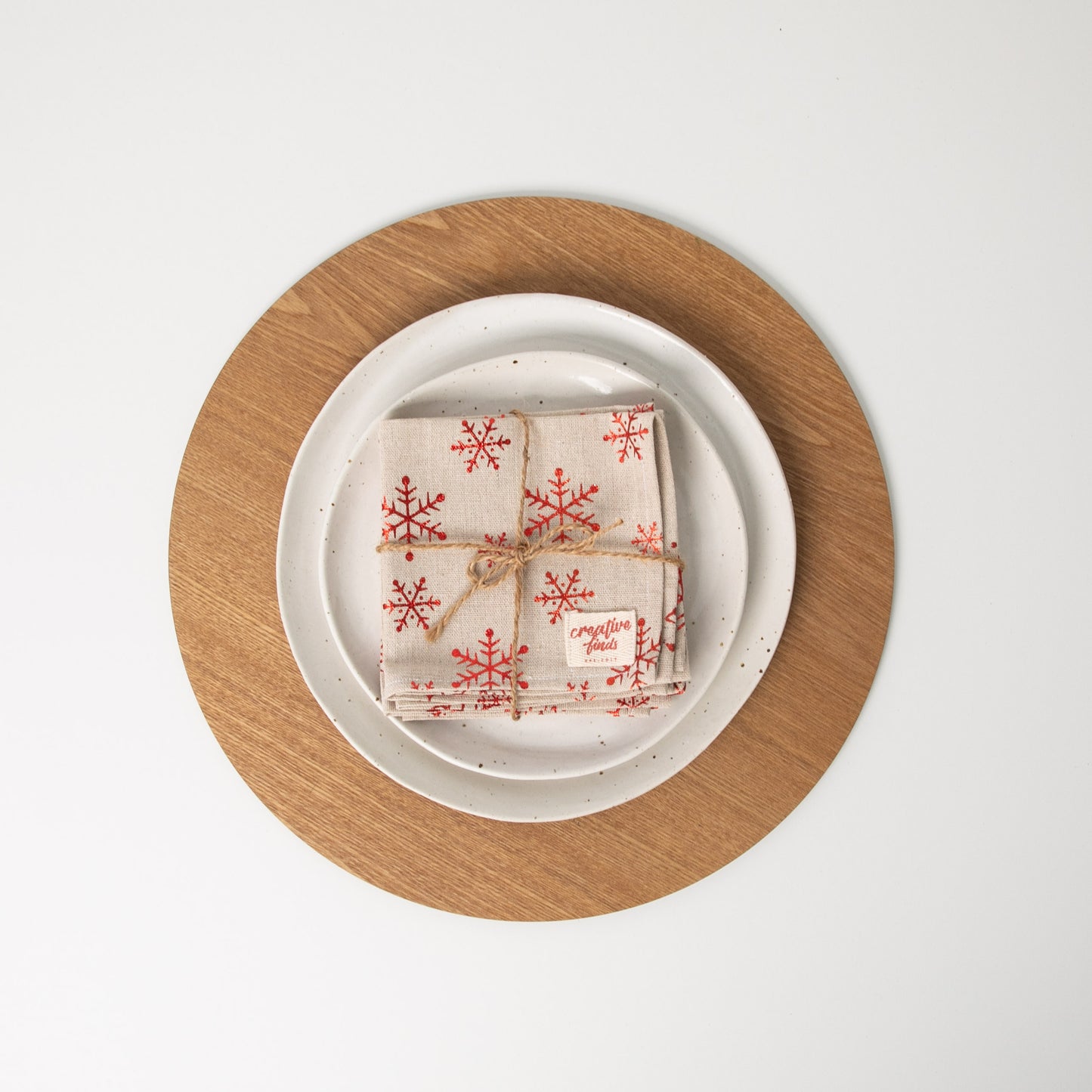 
                  
                    Set of four christmas snowflake napkins tied with string sitting on white plates
                  
                