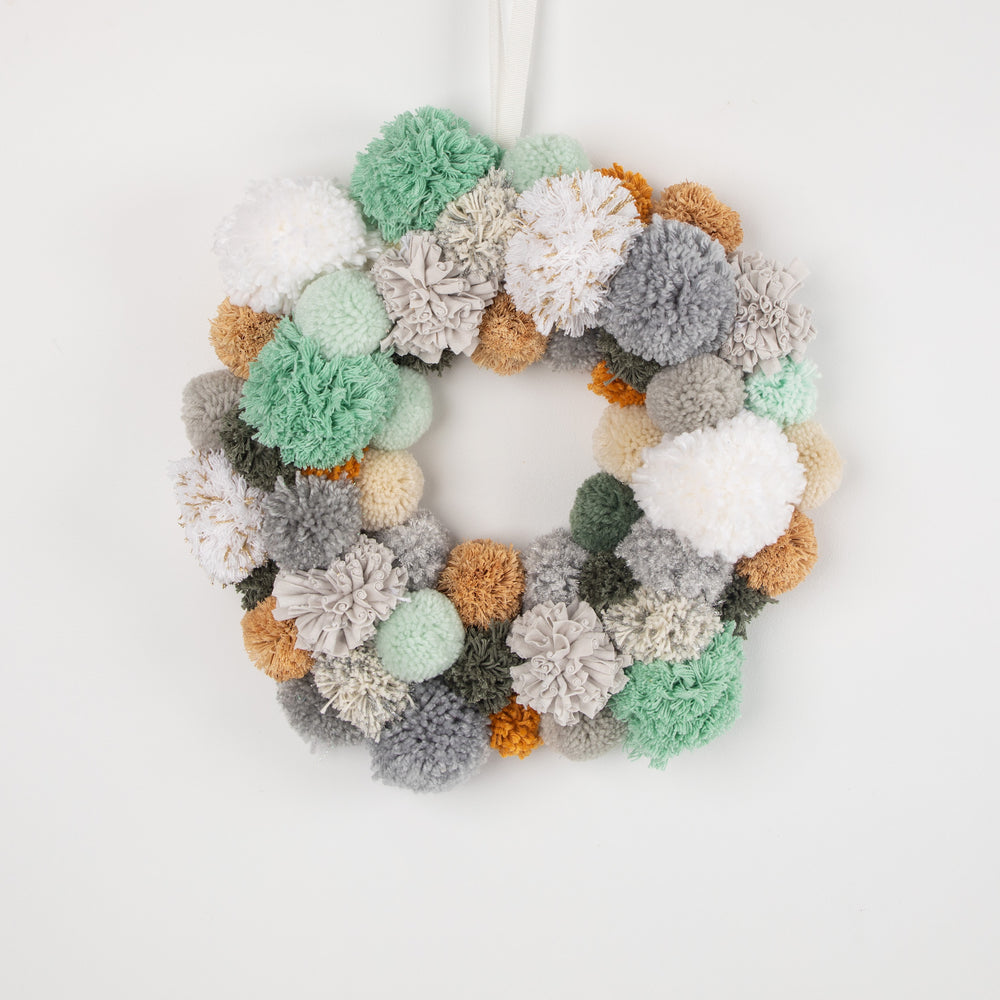 Earthy Cool - greens. PomPom Wreath hanging on white background
