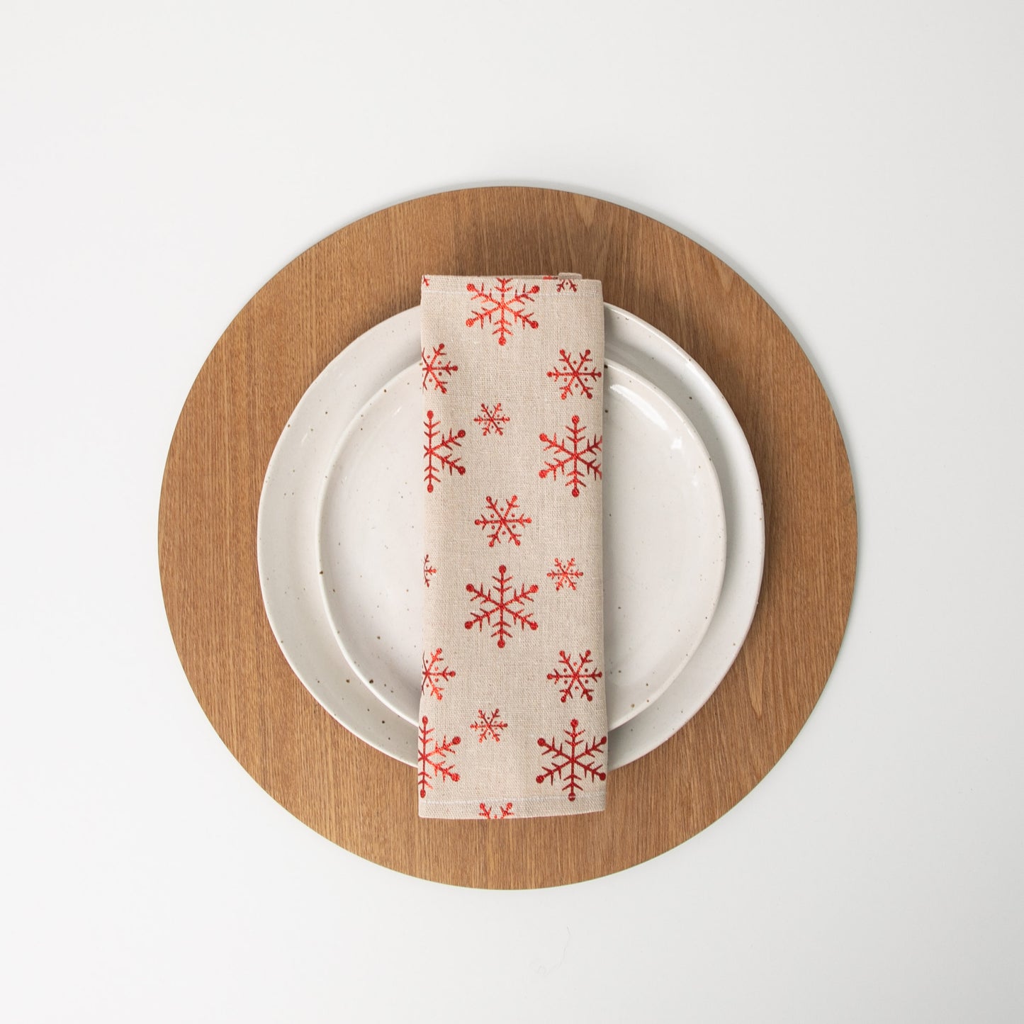 
                  
                    Christmas snowflake napkin folded in thirds and sitting on a white plate
                  
                